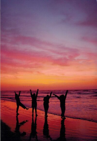 Members dancing on the beach at sunset on a retreat.